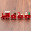 Mini wooden Christmas train set with festive decor on wooden floor, featuring Santa and holiday-themed designs.