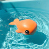 Cute orange clockwork bath toy floating in water, perfect for kids' bath time fun and improving motor skills.