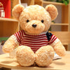 Teddy bear plush toy in red striped sweater sitting on a table, perfect for hugs and gifts.