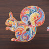 Colorful wooden squirrel-shaped puzzle piece set on a dark wood background, showcasing intricate and vibrant designs.