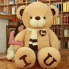 Woman hugging oversized teddy bear plush with love heart and "I U" design in cozy room setting.