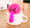 Pink vomiting egg yolk stress toy on a coffee mug for fun and stress relief.