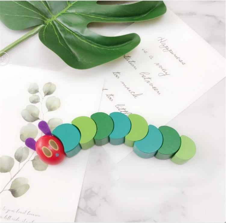 Wooden Hungry Caterpillar Toy on white surface with green leaves, ideal for kids' motor skills development and sensory play.