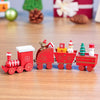 Mini wooden Christmas train set with festive designs, featuring a red engine and decorated carriages on a wooden surface.