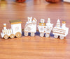 Mini wooden Christmas train set with festive designs on a wooden surface, featuring eco-friendly colors and adorable holiday ornaments.