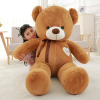 Plush teddy bear doll with ribbon, perfect for snuggling and gifting, shown with a person for size comparison in a cozy room.