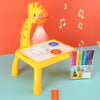 Children's LED Projector Drawing Table with music notes, giraffe design, and colorful pens for art and creativity.