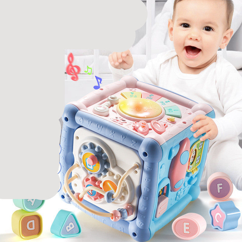 Baby playing with musical activity cube toy featuring lights, sounds, piano keys, and geometric blocks.