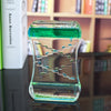 Creative Quicksand Liquid Hourglass with green fluid on a desk for modern home or office décor.