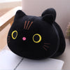 Black plush fat cat doll with cute yellow eyes on chair, soft stuffed animal pillow toy for cuddling and decorating.