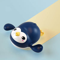 Adorable wind-up swimming penguin bath toy on a light blue background, perfect for baby bath time and Montessori learning.