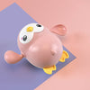 Cute pink wind-up swimming penguin bath toy with yellow feet, perfect for baby bath fun and motor skill development.