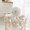 Cute white octopus plush pendant with smiling face on a modern table, perfect for gifts and home décor.