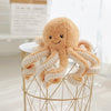 Cute octopus plush pendant with smiling face and elastic legs on round table for decoration or gift.