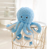 Cute blue octopus plush pendant with big eyes, sitting on a wire frame, perfect for gifts and décor.