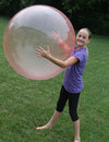 Child playing with inflatable bubble balloon toy outdoors on grass.