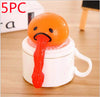 Funny Vomiting Egg Yolk Toy on white mug, stress relief squishy for pranks and laughs, orange egg with red tongue.