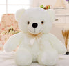 Soft white teddy bear plush toy with a bow, perfect for snuggles and room decor, sitting in a cozy, floral-themed room.