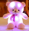 Glowing teddy bear plush toy with LED lights and pink ribbon, soft fabric for bedtime cuddles.