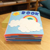 Montessori baby cloth book with colorful felt cover featuring clouds, rainbow, and sun, ideal for early learning and sensory play.