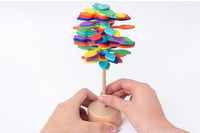 Colorful wooden rotating lollipop toy being spun by hands, designed for stress relief and inspired by the Fibonacci sequence.