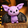 Plush purple bat toy with black wings sitting on a basket, perfect for cuddling and themed decor.