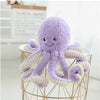 Purple baby octopus plush toy with smiley face on metal stand, soft and huggable for kids' playtime and nursery décor.