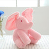 Pink Peek-A-Boo Elephant Plush Toy on table near flower, perfect for interactive play and soothing babies.