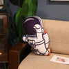 Plush astronaut pillow on a couch, space-themed decor for kids' room, made with soft plush fabric and PP cotton filling.