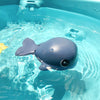 Floating blue whale bath toy swimming in a bathtub for kids' playtime fun and motor skill development.