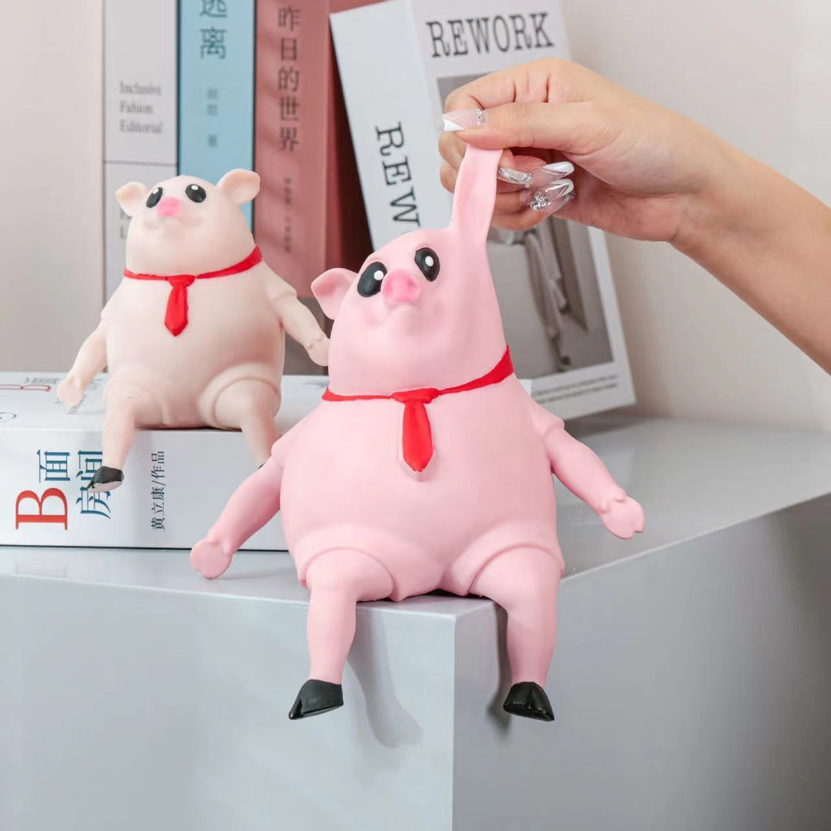 Cute piggy squeeze toy with red tie being stretched for stress relief and sensory play. Ideal for kids and adults, made of soft TPR.