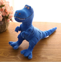 Blue dinosaur plush toy on wooden table, featuring an adorable cartoon Tyrannosaurus design with vibrant colors.