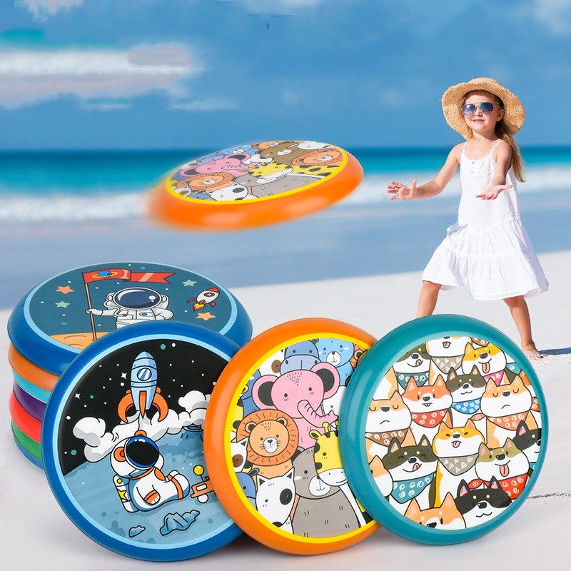 Child playing with colorful kids' flying disc toy on the beach, featuring fun animal and astronaut designs, perfect for outdoor games.