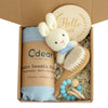 Baby teething toy gift set with muslin swaddle, bunny toy, wooden brush, and milestone disc for soothing and sensory development.