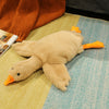 Big white goose plush pillow with orange feet on a cozy bed, perfect for cuddling and decorating.