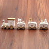 Mini wooden Christmas train set with festive decorations on wooden surface