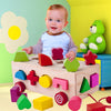 Toddler playing with wooden shape matching building blocks in colorful nursery.