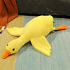 Yellow duck plush pillow on bed, soft and cozy toy for kids and adults.