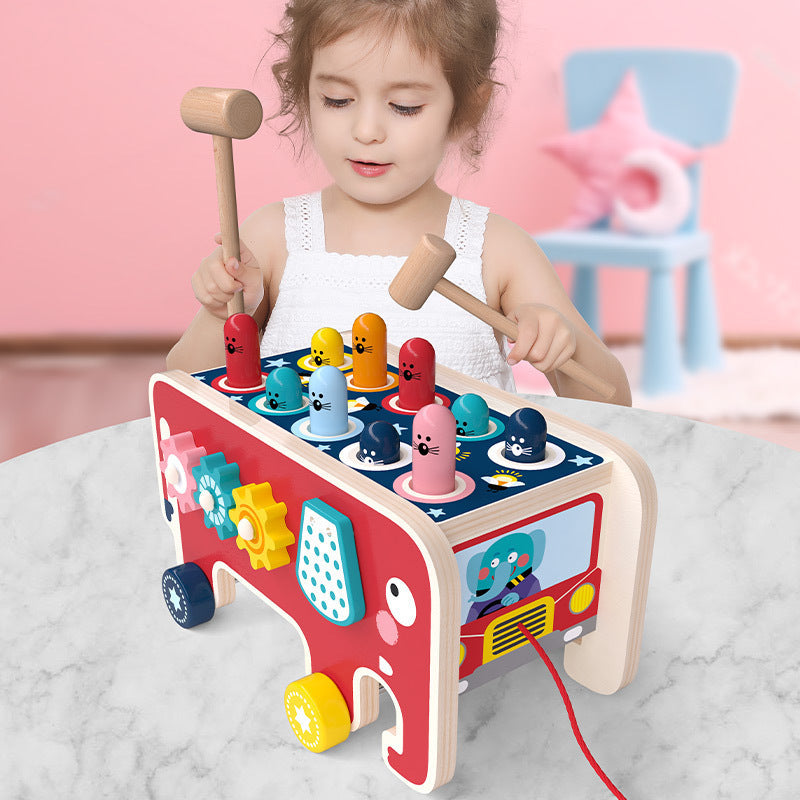 Toddler playing with wooden Montessori pounding bench toy shaped like an animal bus, enhancing motor skills and sensory awareness.