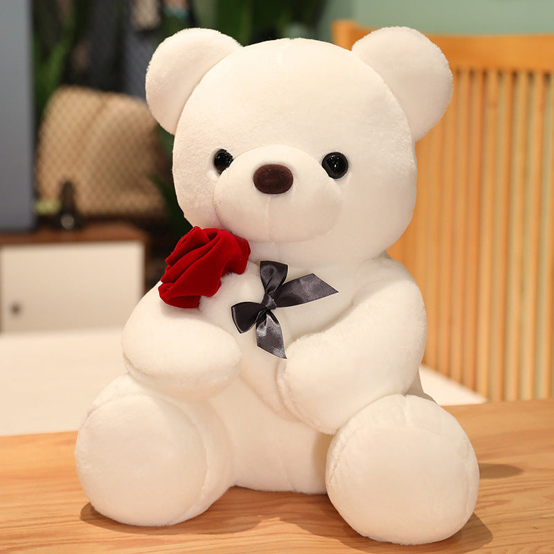 Plush white teddy bear holding a red rose, perfect for gifting and cuddling.