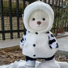 Little Bear Plush Doll in cow-pattern outfit with hood, standing outdoors for creativity and playtime fun.