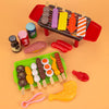 Kids pretend BBQ play set with grill, cookware, and toy food items including skewers, eggs, and sauces for imaginative cooking fun.