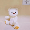 Little Bear Plush Doll in white with changeable clothes, shown sitting on a beige surface, ideal for cuddling and playtime.