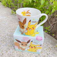 Pikachu and Eeveelution ceramic mug with colorful Pokemon prints, perfect for fans, on a green and grey background.