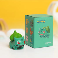 Bulbasaur anime figure next to packaging, part of the Pokemon Figures Toy Set, featuring popular characters like Pikachu and Charmander.