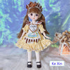 Fashion doll in yellow dress with ribbon and bangs, standing on soft white fur background with decorative lighting.