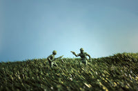 Plastic toy soldiers on grassy field under clear sky, depicting a playful army scene.