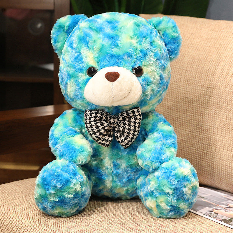 Blue and green teddy bear plush doll with bow tie on sofa, perfect Valentine’s Day or birthday gift for loved ones.