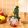 Thanksgiving gnome doll with green hat and autumn decor, perfect for harvest festival decoration on wooden table.