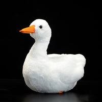 Realistic plush duck toy with soft white fabric and orange beak on a black background